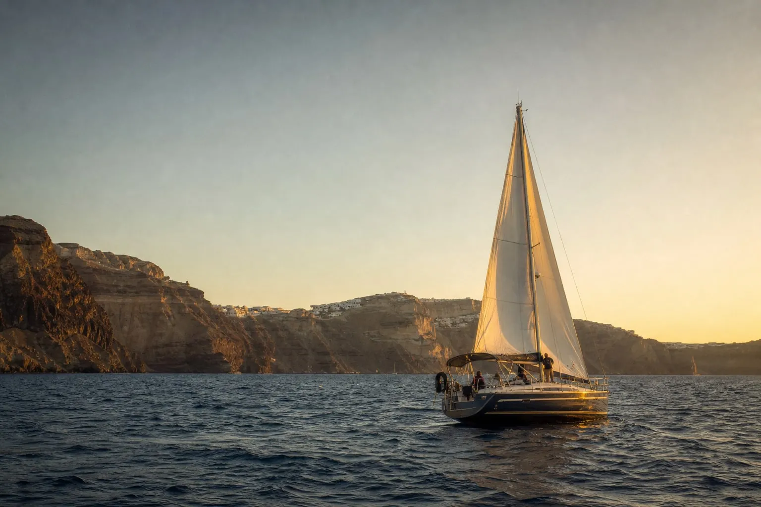 A sailing boat on the Aegean caldera at golden hour