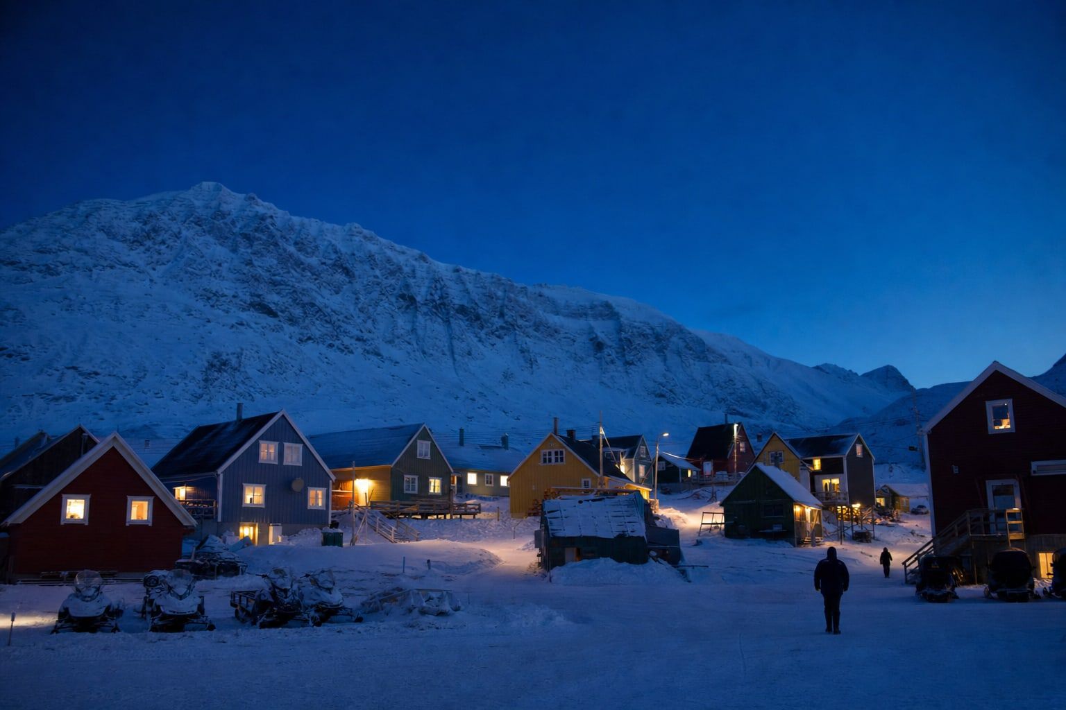 Colourful wooden houses below snowy mountains in Arctic twilight