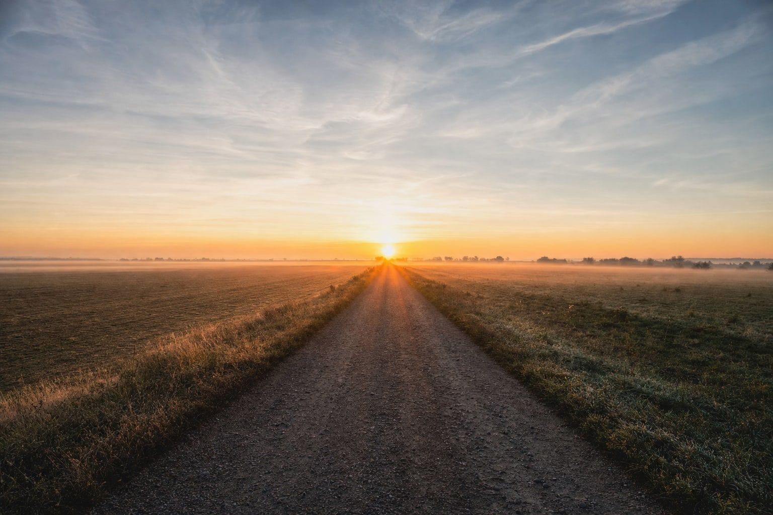 The rising sun at the end of a straight road at the equinox