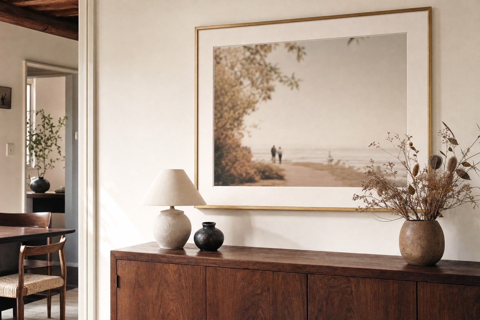 A framed print with a wide mat above a wooden sideboard