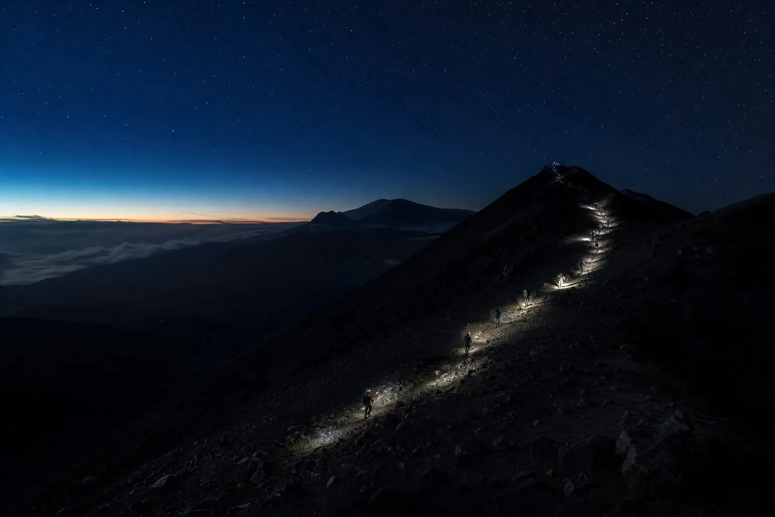 Climbing in the dark Headlamps of climbers on a mountain trail before dawn