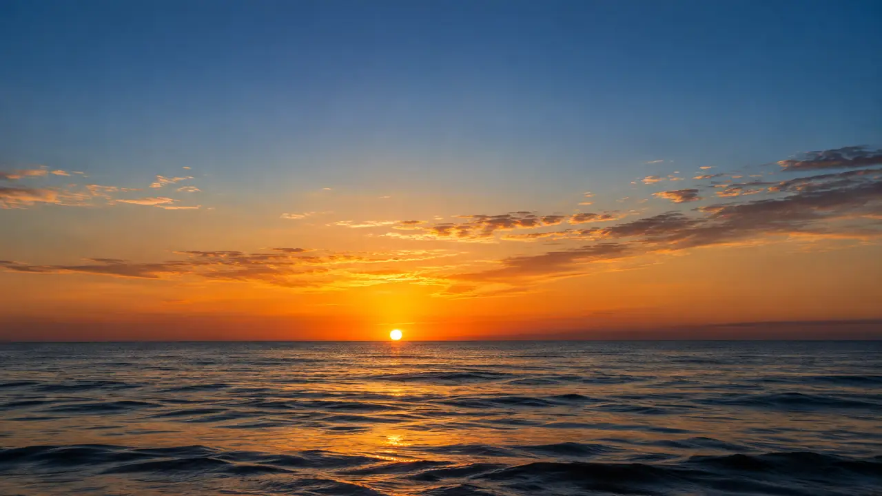 The sun rising over a calm sea at dawn, a path of golden light on the water