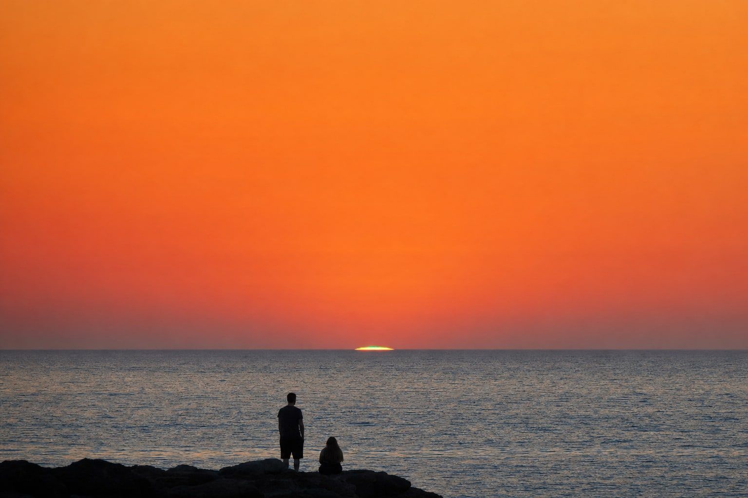 The last sliver of the sun on a clear sea horizon