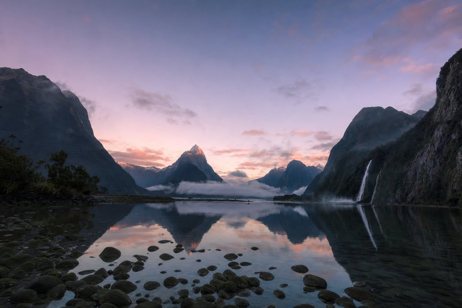Sunrise at Milford Sound Morning light on Mitre Peak above the still water of Milford Sound