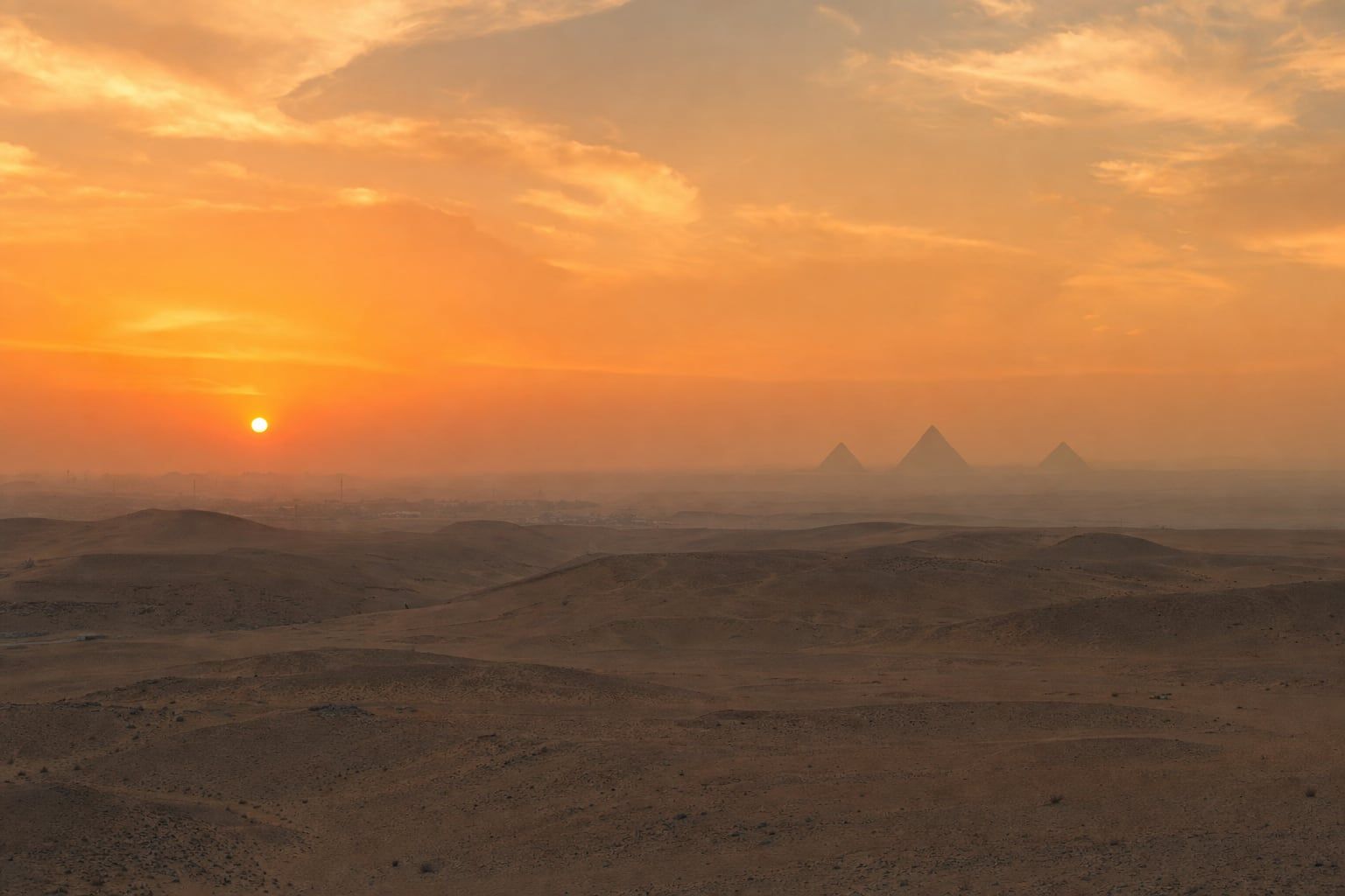 Sunset over the Giza plateau Desert sunset with the Pyramids of Giza as distant silhouettes