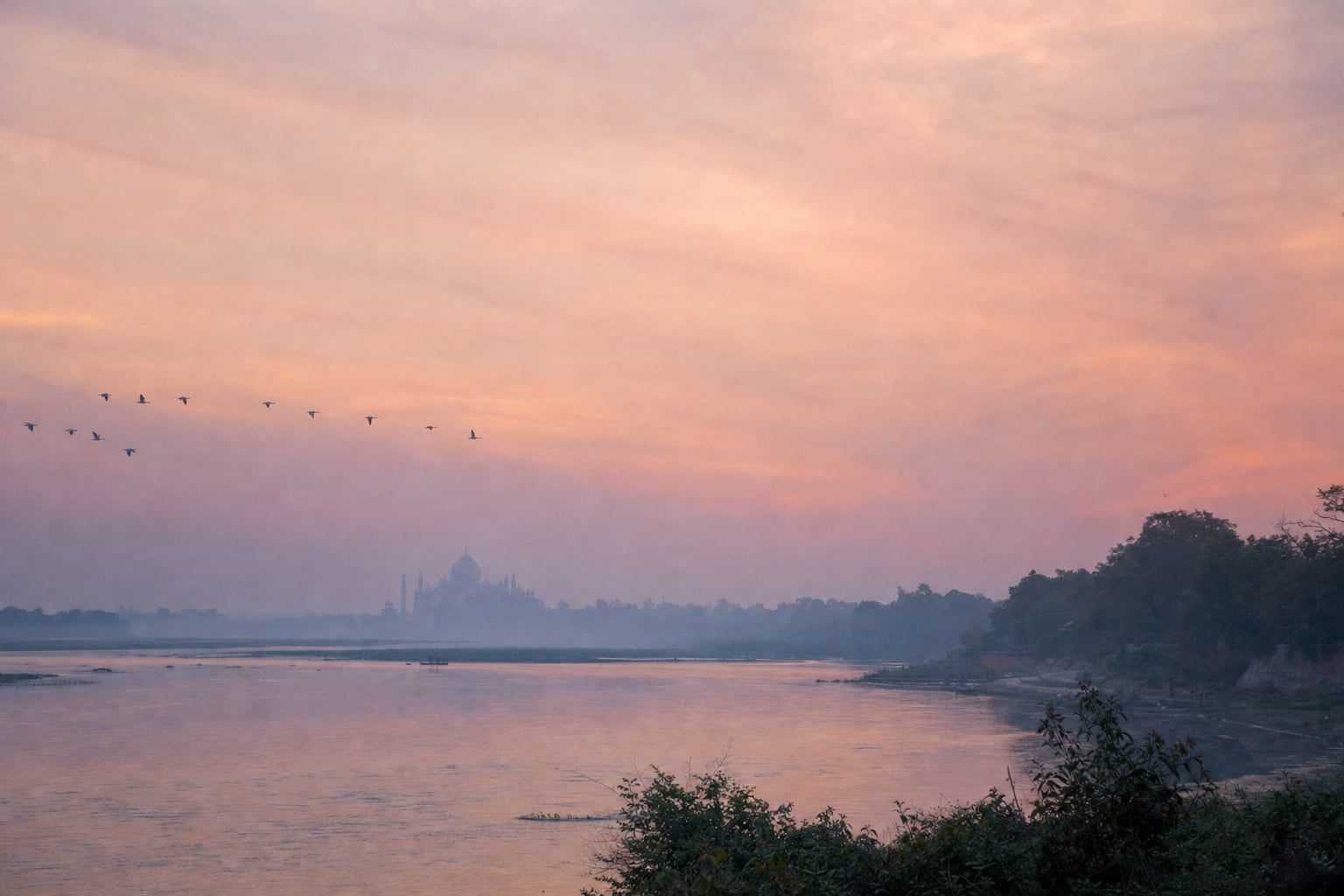 Sunrise over the Taj Mahal, Agra Misty sunrise over the Yamuna River with the Taj Mahal far in the distance