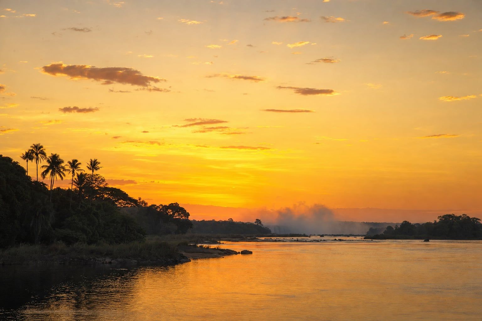 Sunset over the Zambezi, Victoria Falls Golden sunset over the Zambezi River with mist rising from Victoria Falls far away