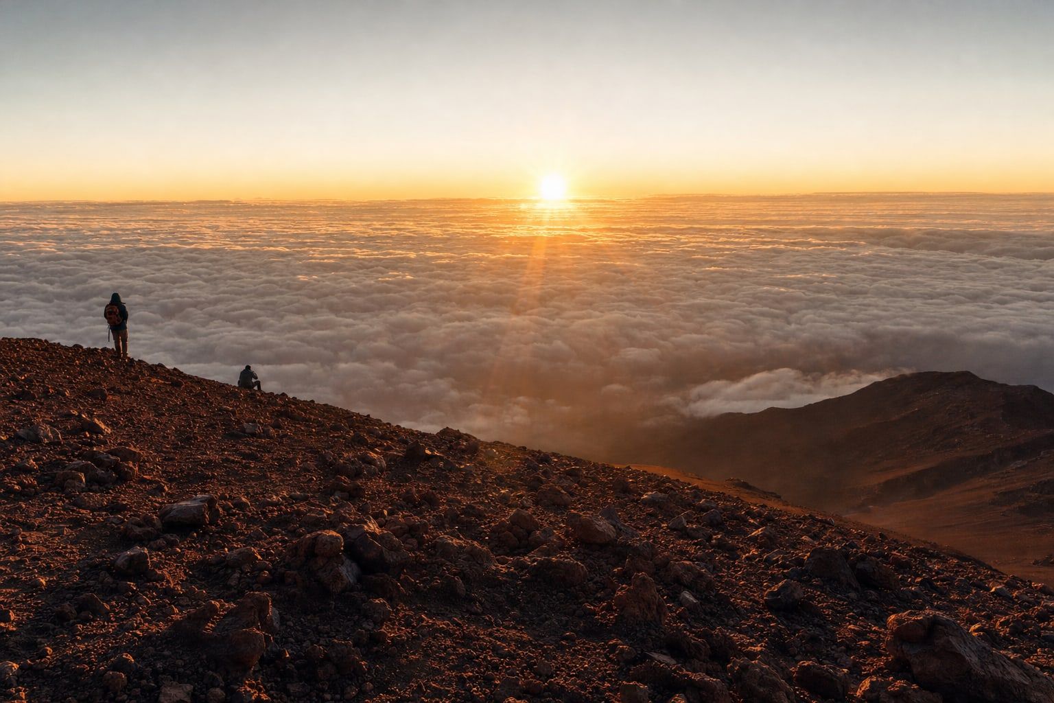Sunrise above a sea of clouds from a volcanic summit