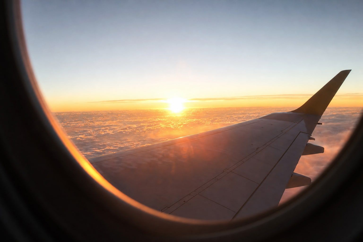 Sunrise seen through an airplane window above the clouds