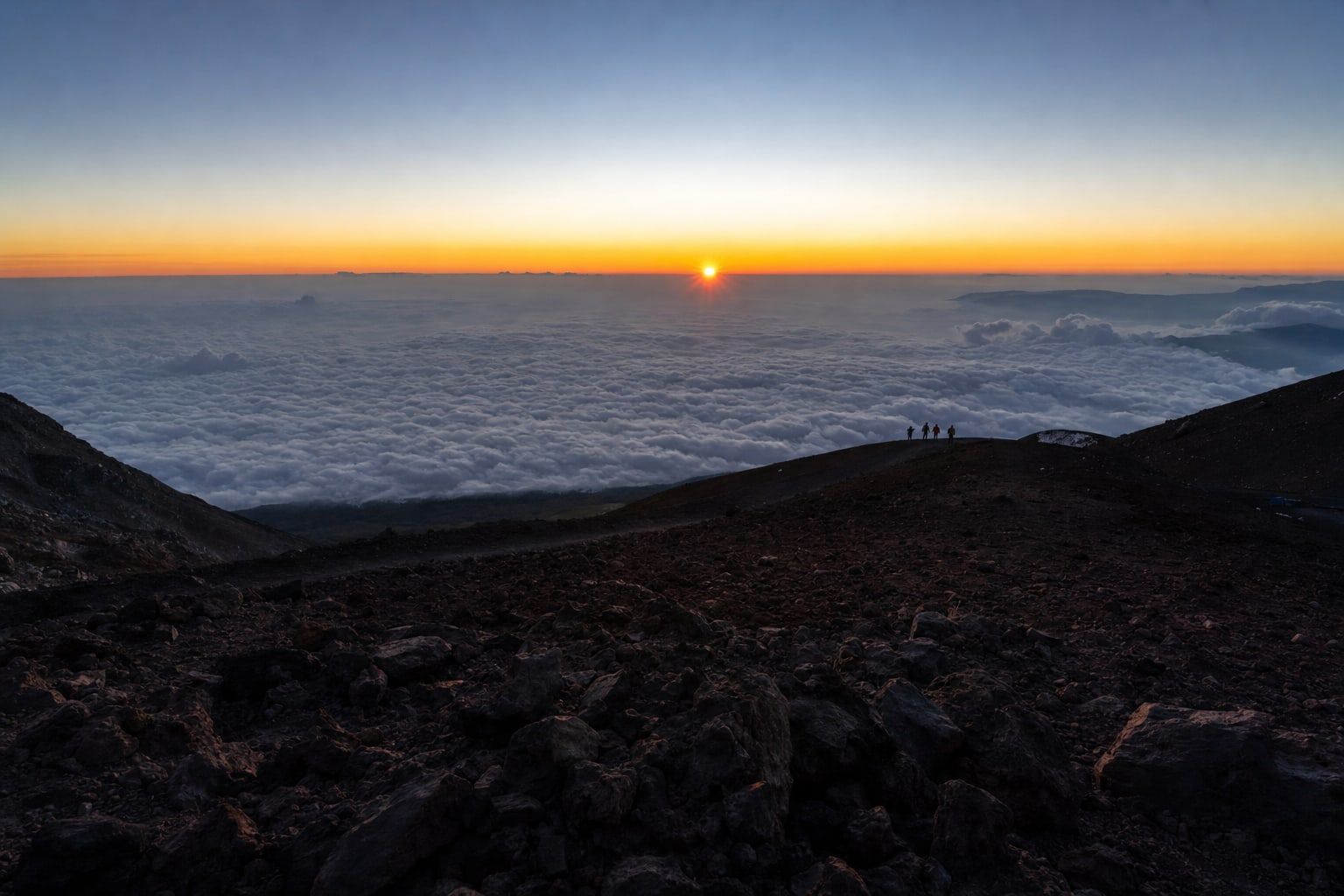 Sunrise over a sea of clouds from a high volcanic summit